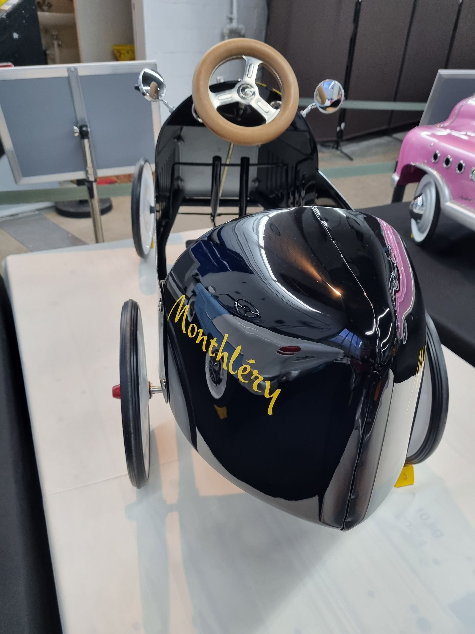 Ein schwarzes Tretauto mit der Aufschrift „Monthlezzy“ darauf